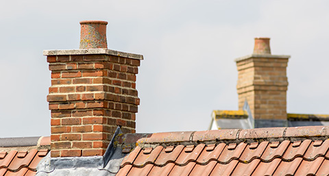 two chimneys on top of modern roofs of houses