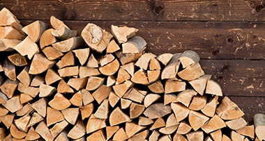 firewood stacked up against a wooden wall