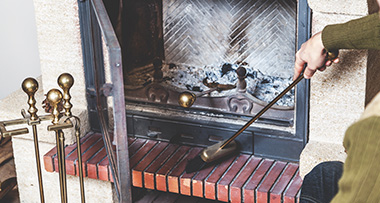 a person using a brush sweeping the area around a fireplace