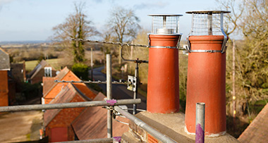 two chimneys on a roof with cowls covering them