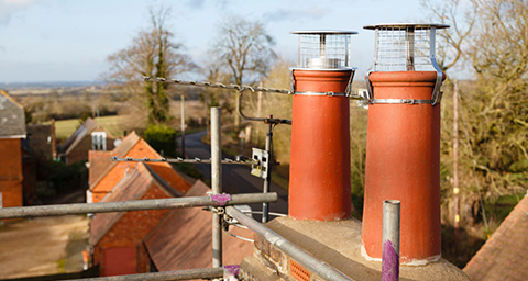 two chimney cowls on top of a roof next to radio antennas 