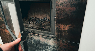 a person opening a fireplace in preparation for a clean