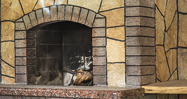 a dirty fireplace surrounded by a brown brick structure 