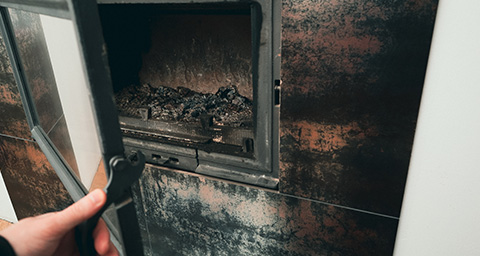 a person opening a dirty fireplace